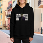 On-location model photograph displaying a suited clown portrait against a newspaper-style text collage on the front of a women's hoodie
