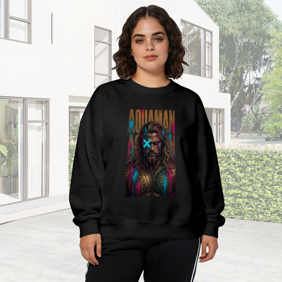 Outdoor photograph of a model in a women's crewneck sweatshirt bearing a tall bearded graffiti portrait with a cyan X across the eyes