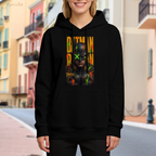 On-location model photograph displaying a tall graffiti-style cowl portrait with a green X across the eyes on the front of a women's hoodie