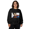 Women's crewneck sweatshirt seen on a model, its front graphic depicting a tightly cropped intense face above a cape against newsprint