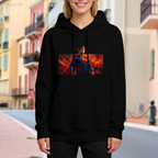 Outdoor photograph of a model in a women's hoodie bearing a caped figure in a wide portrait framed by flame-like color