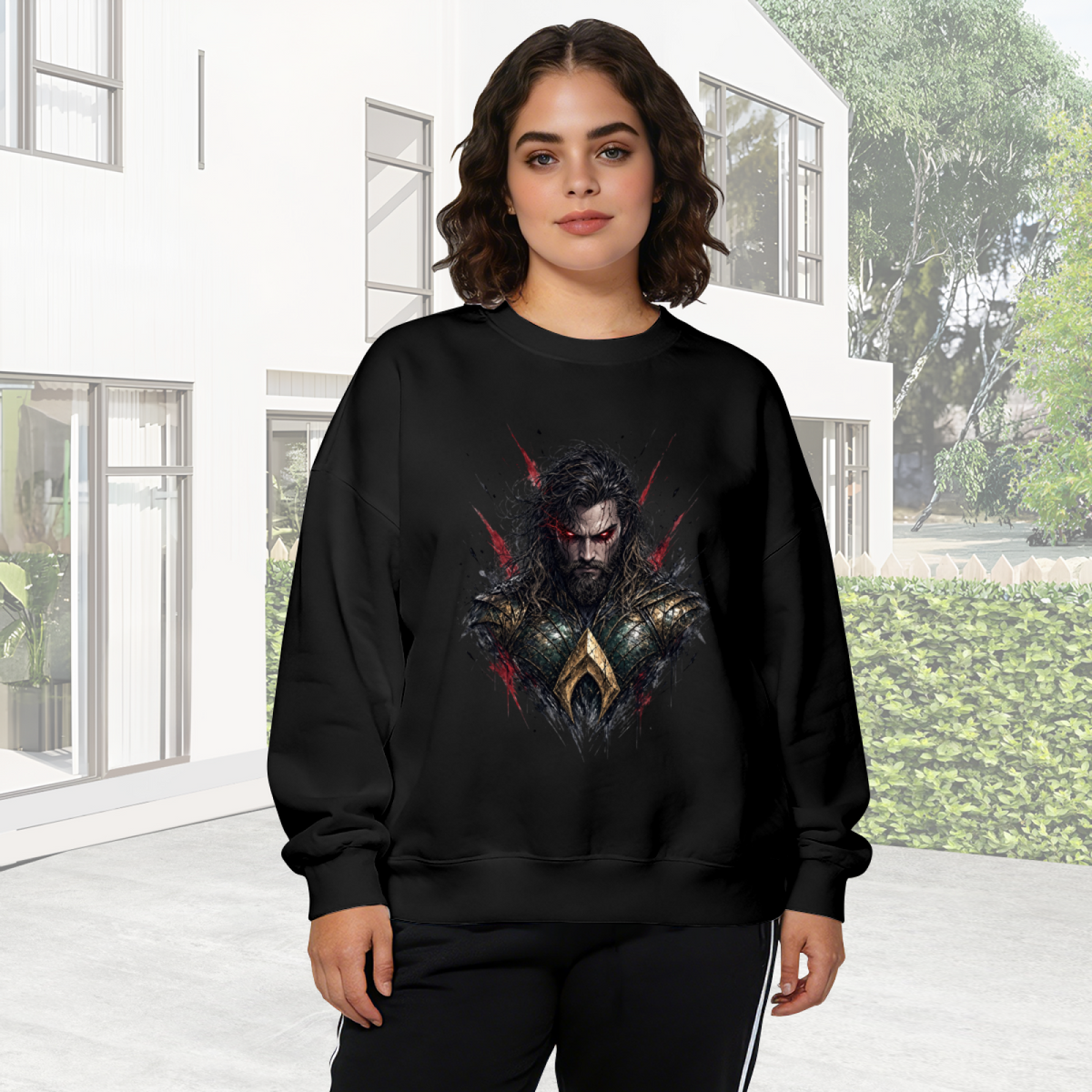 Outdoor photograph of a model in a women's crewneck sweatshirt bearing a centered bearded warrior portrait with red eyes and rough dark edges