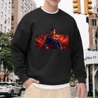 A caped figure in a wide portrait framed by flame-like color visible on a men's crewneck sweatshirt in an outdoor front model view