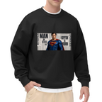 Studio photograph of a model in a men's crewneck sweatshirt showing a classic caped figure posed against a rectangular newspaper-style collage