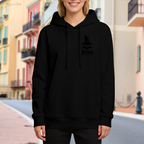 A small pointed-cowl silhouette with ink-style lettering visible on a women's hoodie in an outdoor front model view