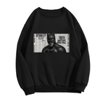 Standalone men's crewneck sweatshirt front displaying a graphic of a monochrome cowl portrait layered over a newspaper-style panel