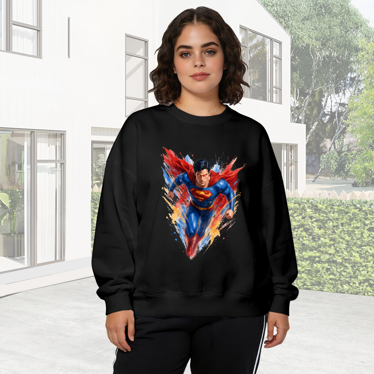 Lifestyle image outdoors: women's crewneck sweatshirt with a front graphic of a flying caped figure amid sharp multicolored brushstrokes