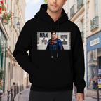 Outdoor photograph of a model in a men's hoodie bearing a classic caped figure posed against a rectangular newspaper-style collage