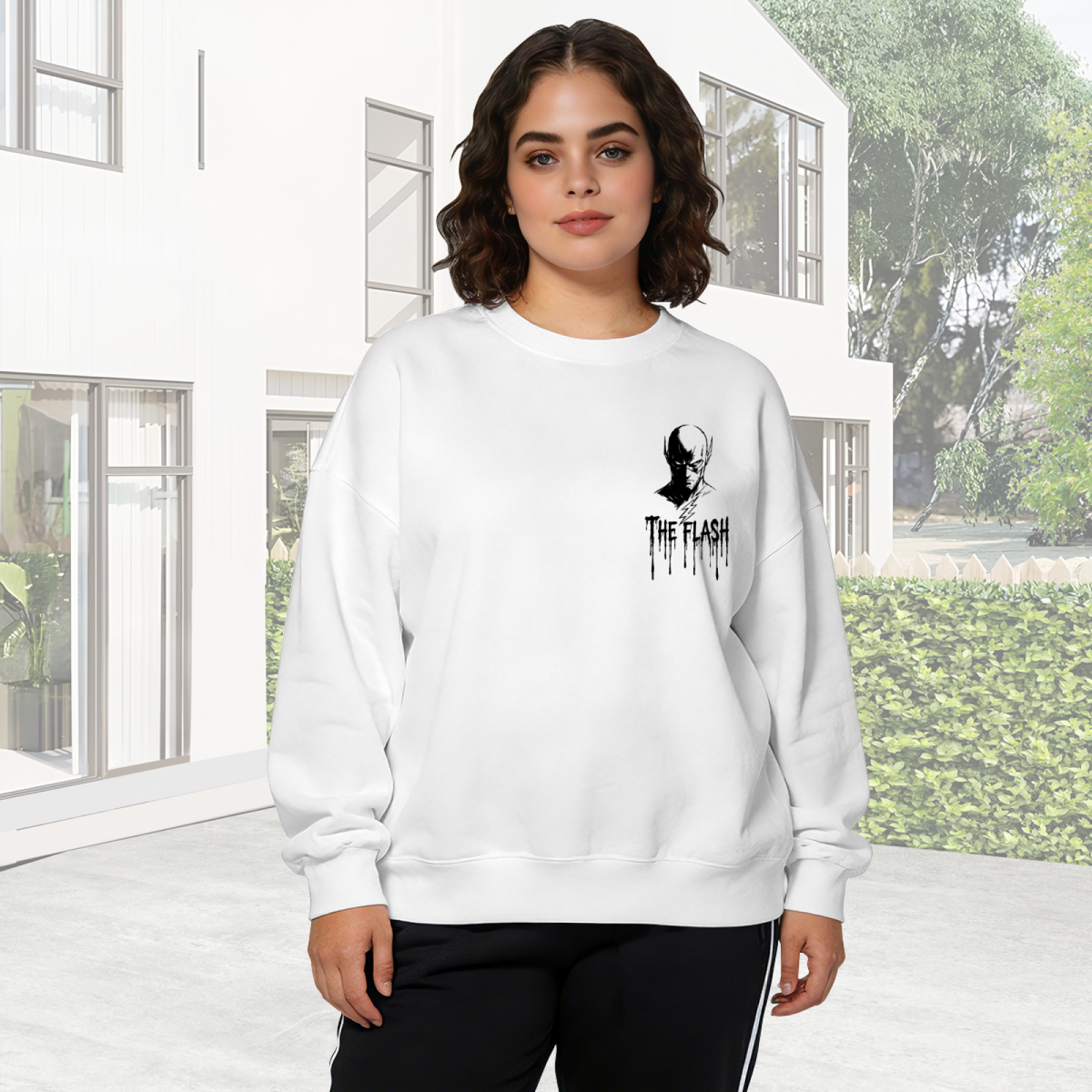 A small masked silhouette with lightning-themed ink lettering visible on a women's crewneck sweatshirt in an outdoor front model view